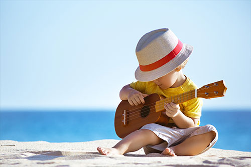 kid playing guitar on beach